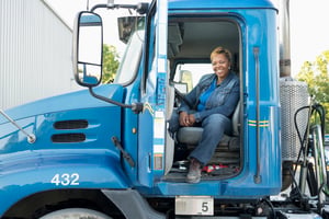A female truck driver smiling in the front seat - Managing risk