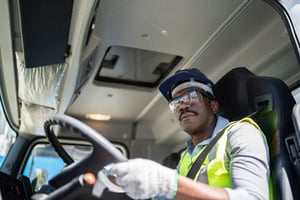 A trucker drives his semi while wearing safety gear