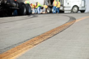 tire marks on a highway in front of workers cleaning up a semi crash scene