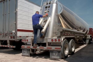 truck driver climbing up back ladder of a semi trailer 